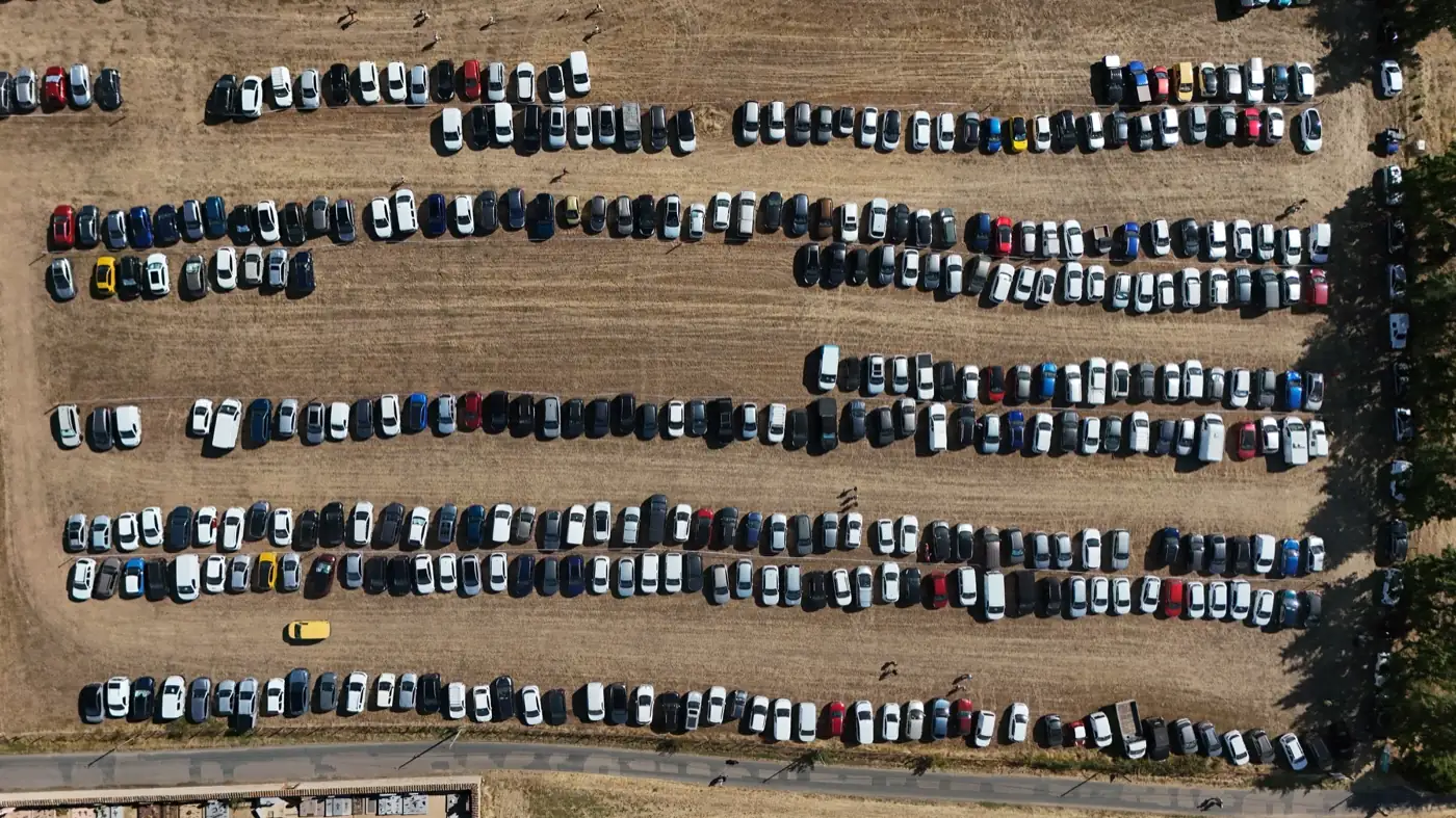Vue aérienne verticale du parking de la fête, plusieurs centaines de voitures rangées en lignes