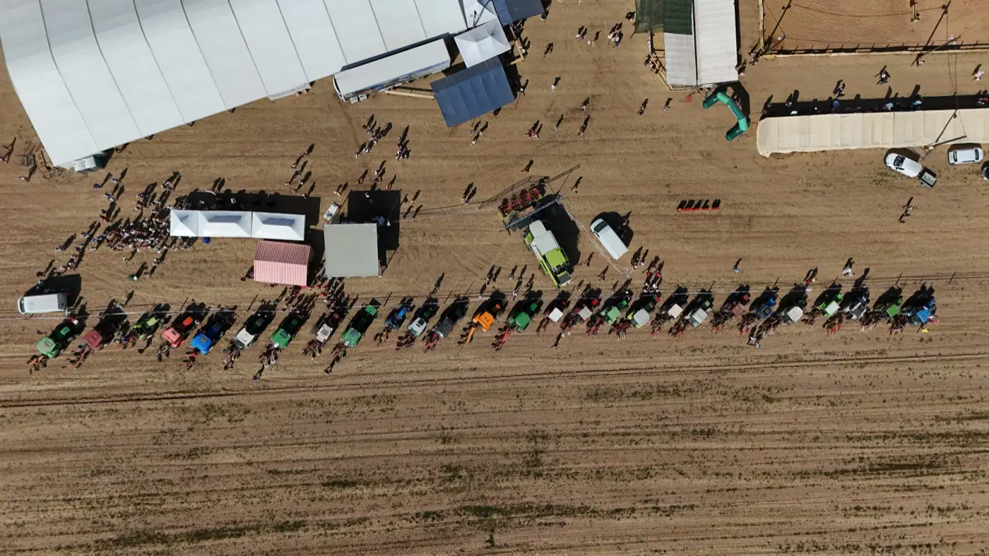 Vue aérienne verticale de la file de tracteurs et du public rassemblé pour la bénédiction