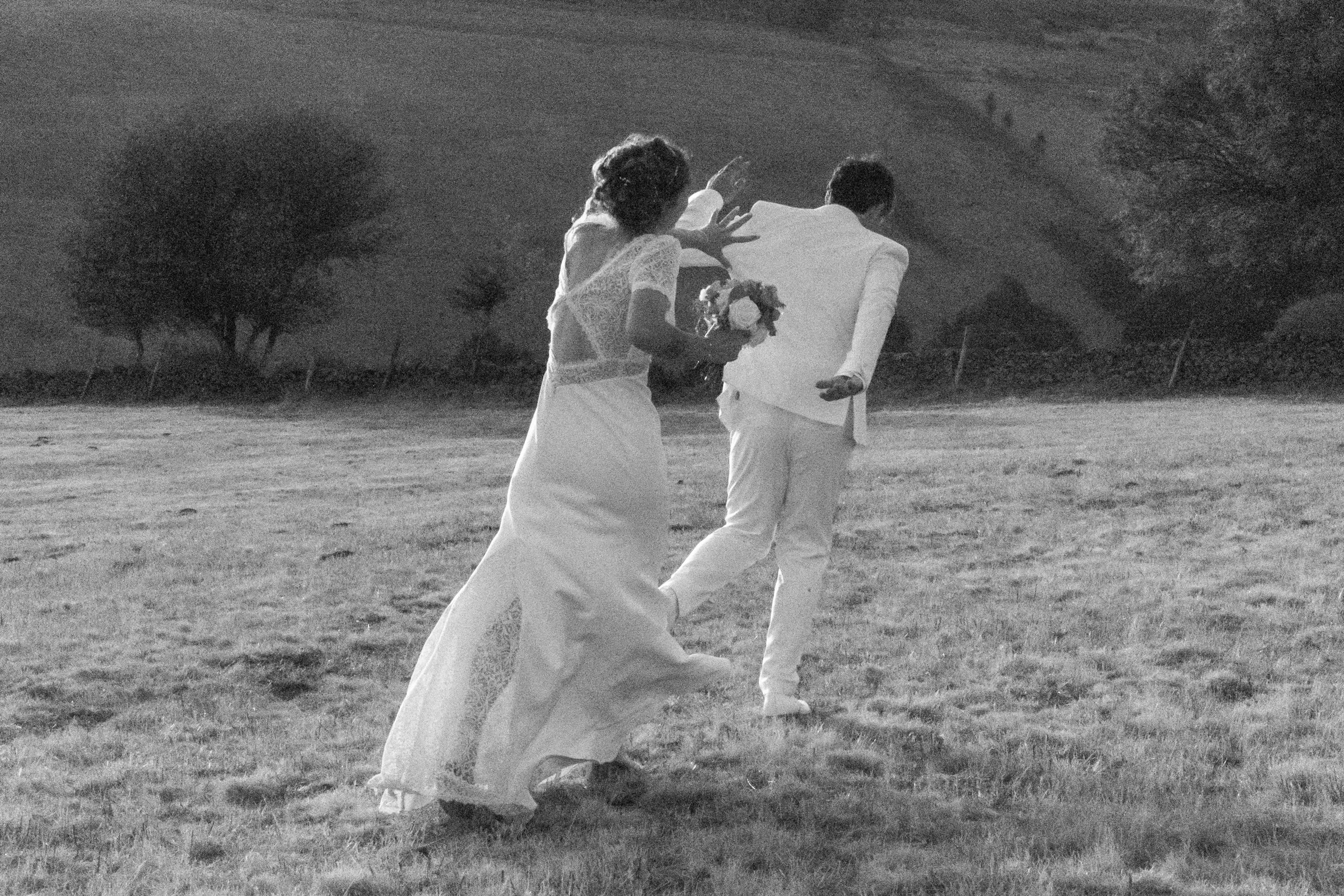 Les mariés courent dans un champ pendant leur séance photo